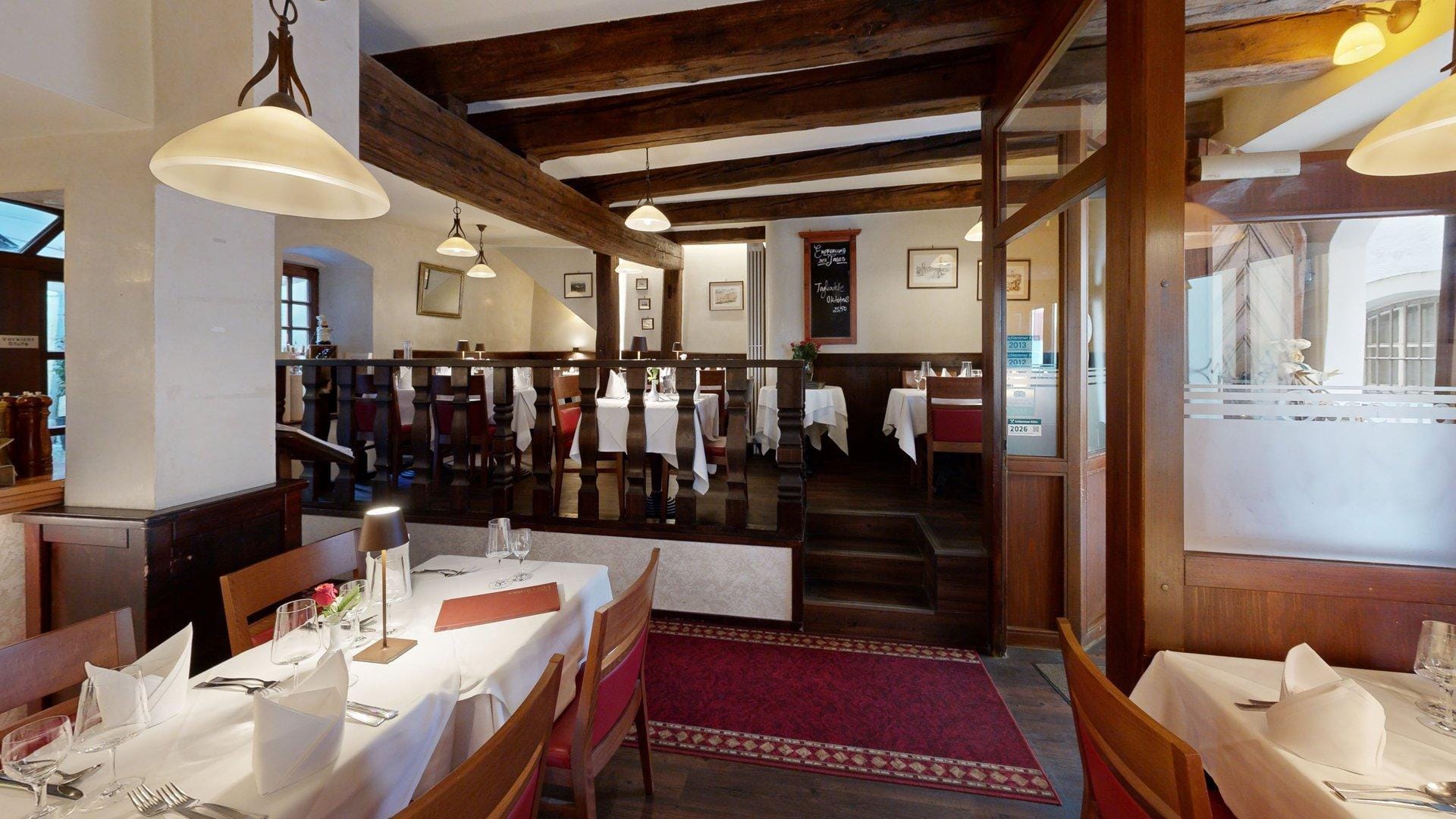 Gastraum der Osteria Luna Rossa mit Holztreppe und rustikalen Holzbalken